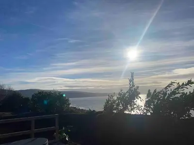 a view of the ocean with the sun in the sky at Ocean View with hot tub in Barmouth