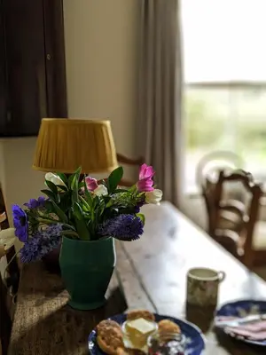 a table with a vase of flowers and a plate of food at Garden View Apartment in Oswestry