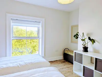 a white bedroom with a bed and a window at Family Home in Tywyn - Game and Cinema Rooms in Tywyn