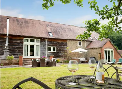 a table with a bottle of wine and two glasses at Oak Barn, Ludlow in Ludlow
