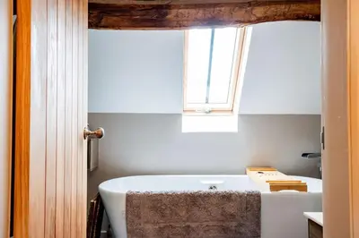 a white bath tub in a bathroom with a window at Oak Barn, Ludlow in Ludlow