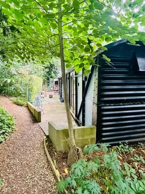 a tree sitting next to a building with a staircase at The Railway Carriage - Blue in Glasbury
