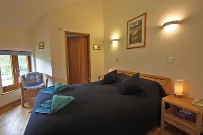 a bedroom with a large bed and a chair at Henllys Lodge in Cilycwm