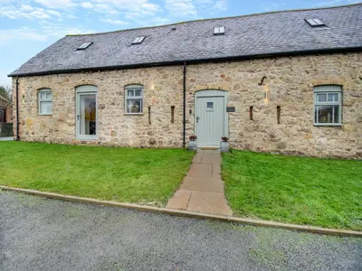 a stone building with a door and a grass yard at Hares Hollow - Uk33953 in Llanymynech