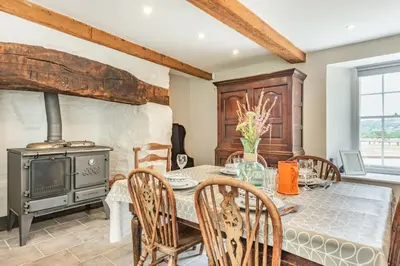 a dining room with a table and a wood stove at Ty Glyn Mansion Cottage in Ciliau-Aeron