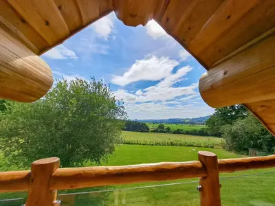 a view from a log cabin window with a view of a field at Hope Hideaway in Leighton