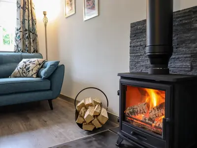 a fireplace in a living room with a blue couch at Bwthyn Camlan in Machynlleth