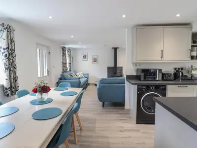 a kitchen and living room with a long table and blue chairs at Bwthyn Camlan in Machynlleth