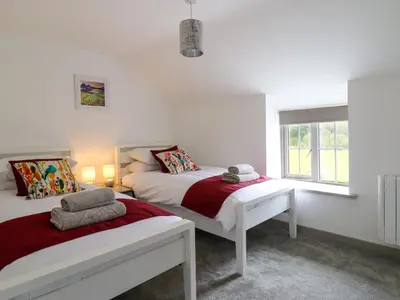 a white bedroom with two beds and a window at Bwthyn Camlan in Machynlleth
