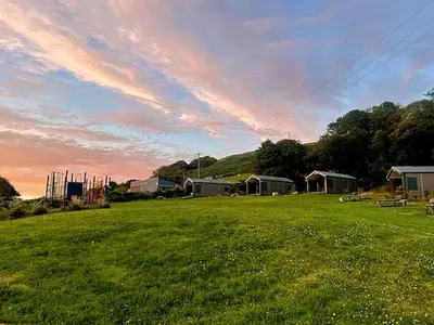 a field of grass with a sunset in the background at Cabin Cynthia in Llwyngwril