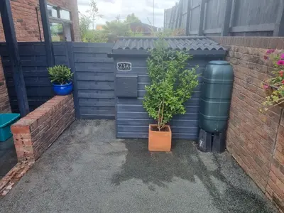 a garden with two potted plants and a fence at 1-Bed Apartment - Sleeps 2 & Private Parking in Llansantffraid-ym-Mechain