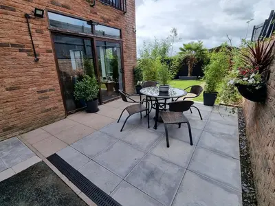 a patio with a table and chairs and a brick building at 1-Bed Apartment - Sleeps 2 & Private Parking in Llansantffraid-ym-Mechain