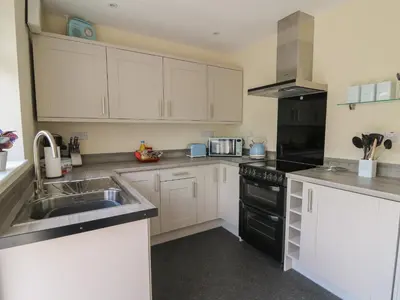 a kitchen with white cabinets and a sink at Nuthatch Cottage at Riverside Lodge in Rhayader