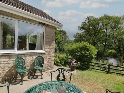 a patio with two chairs and a table at Nuthatch Cottage at Riverside Lodge in Rhayader