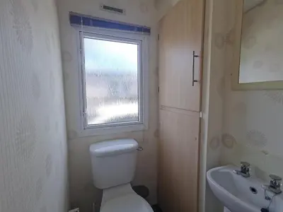 a bathroom with a toilet and a sink and a window at Snowdonia Holiday Sea Beach and Mountains view in Llwyngwril