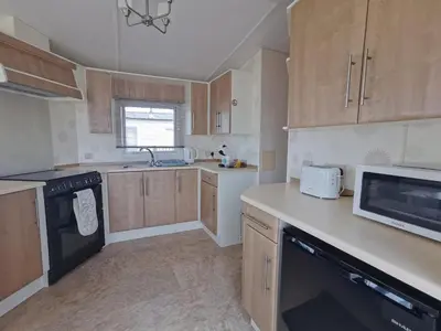 a kitchen with wooden cabinets and a counter top at Snowdonia Holiday Sea Beach and Mountains view in Llwyngwril