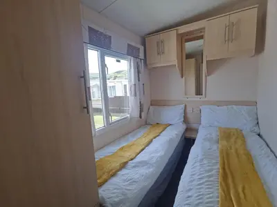 two beds in a small room with a window at Snowdonia Holiday Sea Beach and Mountains view in Llwyngwril