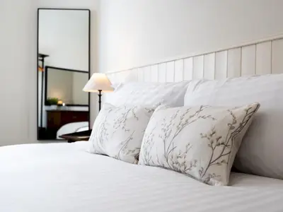 a white bed with white pillows and a mirror at School House Victorian elegance by the river with parking Pass the Keys in Shrewsbury