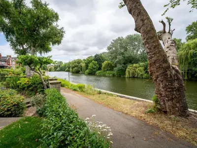a walkway next to a river with a tree at School House Victorian elegance by the river with parking Pass the Keys in Shrewsbury