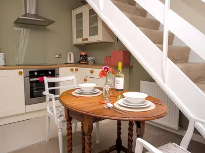 a small kitchen with a wooden table and a staircase at The Lilley Pad in Ludlow Cosy, Central, Perfect for Couples, Netflix & Parking Permit in Ludlow