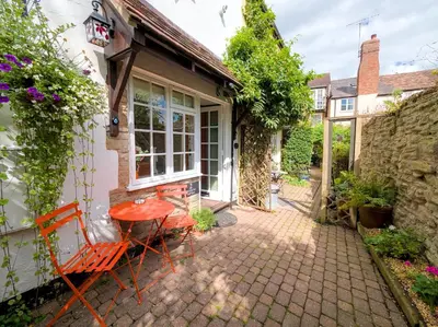 a patio with a red table and chairs in front of a house at The Lilley Pad in Ludlow Cosy, Central, Perfect for Couples, Netflix & Parking Permit in Ludlow