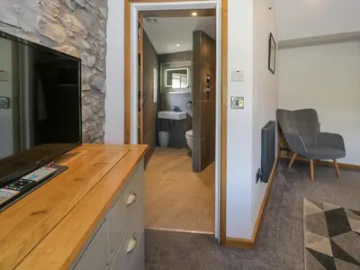a living room with a tv and a bathroom at Y Bwthyn in Dolgellau
