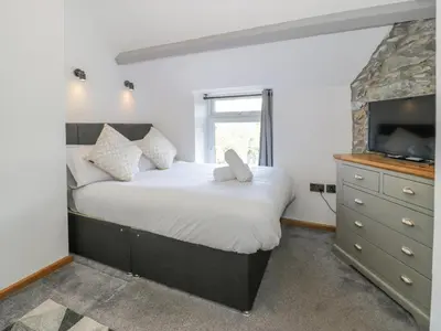 a bedroom with a large bed and a television at Y Bwthyn in Dolgellau