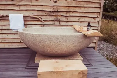 a stone bath tub sitting on a wooden deck at Birch Banc Retreats - Glyn-Haul, New Enc Decking in Llanidloes