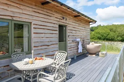 a patio with a table and chairs on a wooden deck at Birch Banc Retreats - Glyn-Haul, New Enc Decking in Llanidloes