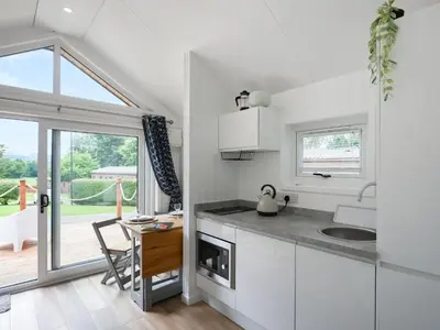 a kitchen with white cabinets and a table and a dining room at Mini Lodge - Uk47682 in Montgomery