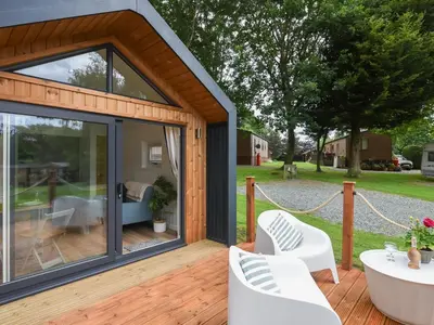 a house with a glass door and white chairs on a deck at Mini Lodge - Uk47682 in Montgomery