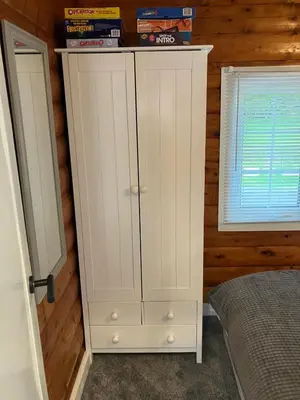 a white cabinet in a bedroom next to a window at Snowdonia luxury log cabin in Trawsfynydd