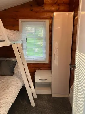 a bedroom with a bunk bed and a ladder and a window at Snowdonia luxury log cabin in Trawsfynydd