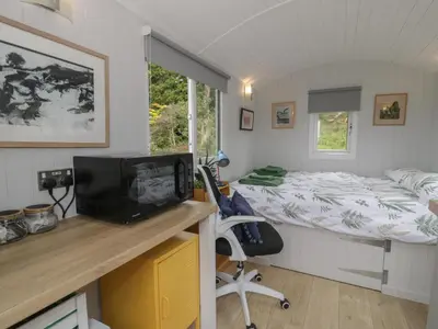 a bedroom with a bed and a desk with a television at Shepherd's Hut at Penrallt Goch in Blaenau-Ffestiniog