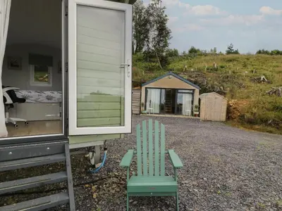 a green chair sitting outside of a trailer at Shepherd's Hut at Penrallt Goch in Blaenau-Ffestiniog