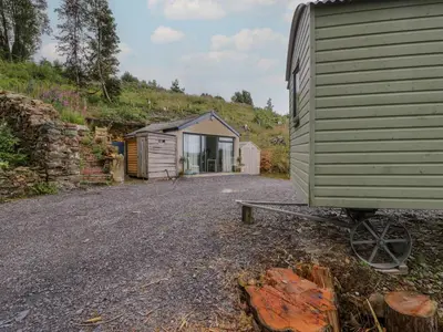 a large green building with a house in the background at Penrallt Bach in Blaenau-Ffestiniog
