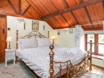 a bedroom with a bed with a wooden ceiling at Violet Cottage in Llangammarch Wells
