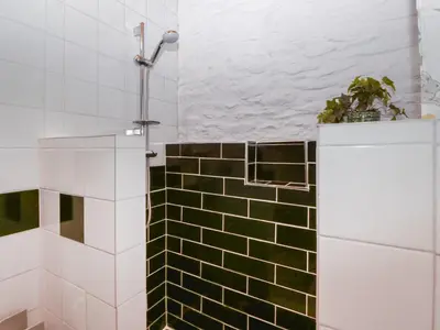 a bathroom with a green and white tiled shower at Violet Cottage in Llangammarch Wells