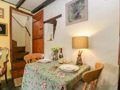 a table with a green table cloth and a lamp at Violet Cottage in Llangammarch Wells