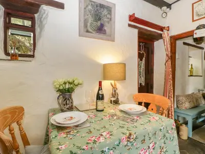 a table with a bottle of wine and flowers on it at Violet Cottage in Llangammarch Wells