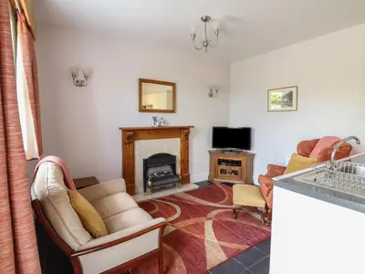 a living room with a fireplace and a couch at Ty Llaeth Cottage in Tywyn