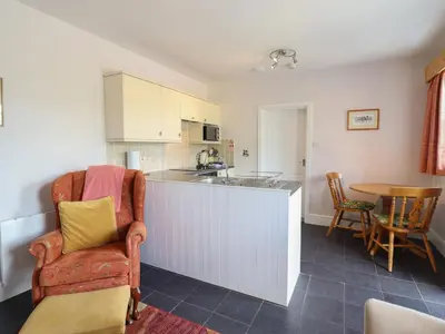 a kitchen with a counter and a chair and a table at Ty Llaeth Cottage in Tywyn