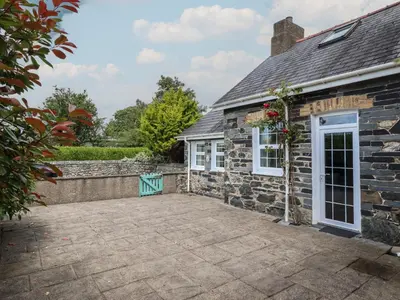 an external view of a stone house with a patio at Bwthyn y Gwas in Tywyn