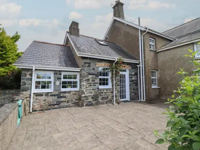 a stone house with a driveway in front of it at Bwthyn y Gwas in Tywyn