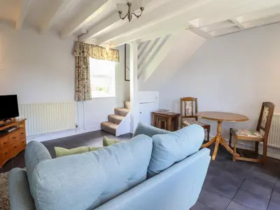 a living room with a blue couch and a table at Bwthyn y Gwas in Tywyn