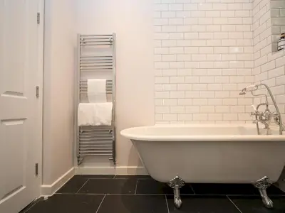 a bathroom with a white tub and a black tile floor at 2 bedroom home within walking distance of the town - Pass the Keys in Shrewsbury