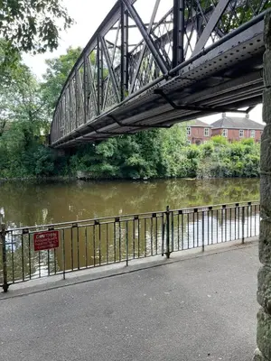 a bridge over a river with a sign on it at St Julians house in Shrewsbury