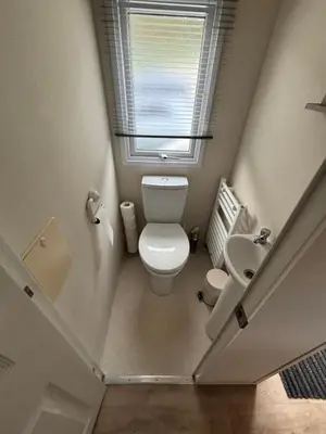 a small bathroom with a toilet and a window at Modern 2017 model Delta Sienna static caravan in Clarach Bay in Aberystwyth