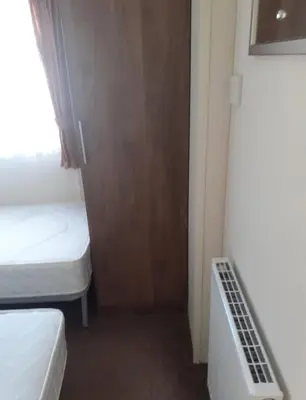 a small room with two beds and a closet at Modern 2017 model Delta Sienna static caravan in Clarach Bay in Aberystwyth
