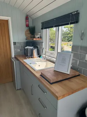 a kitchen counter with a sink and a window at Bay View shepherds hut with hot tub in Llanfair